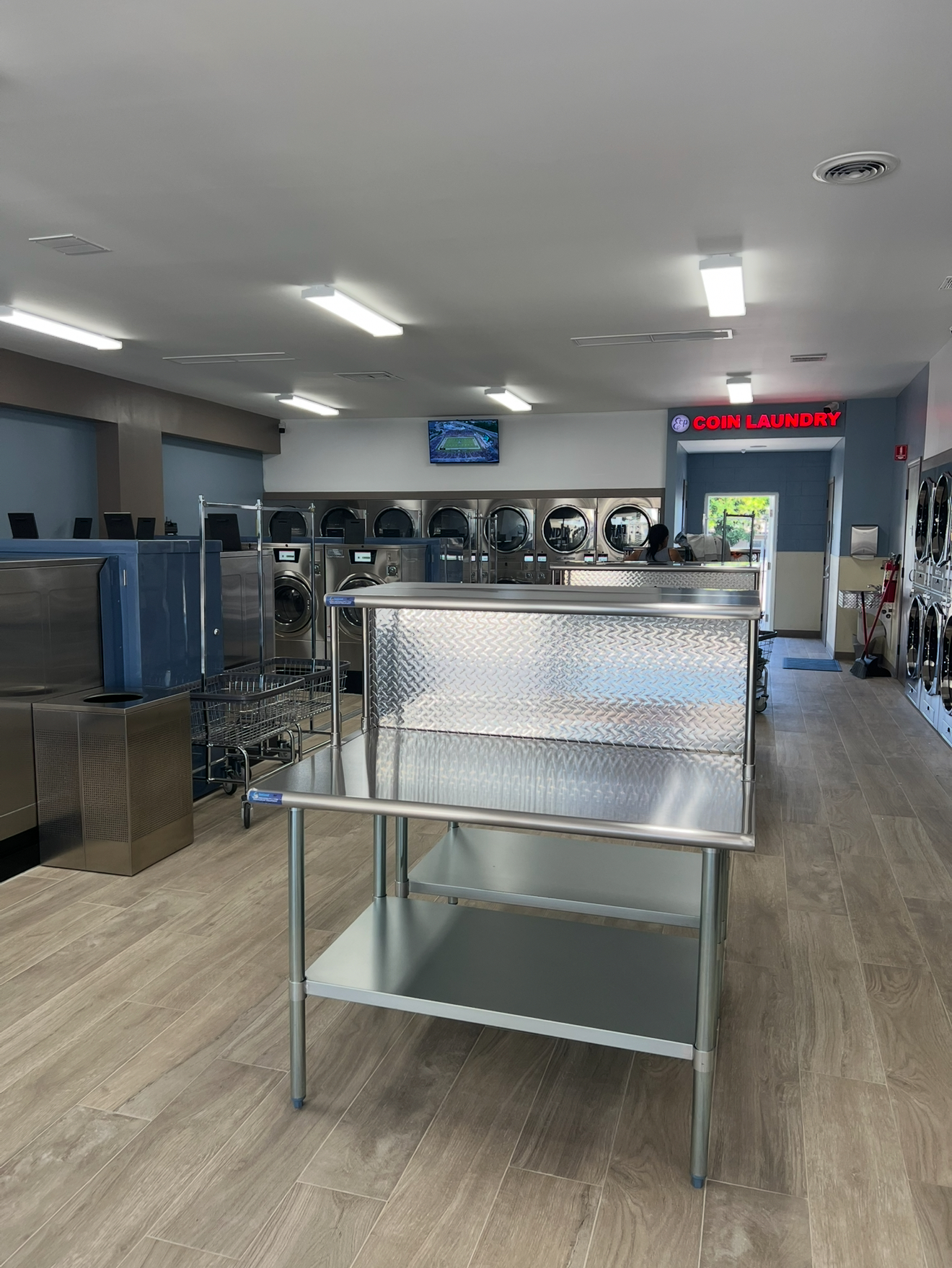 ECP Coin Laundry Arcadia folding area featuring professional stainless steel folding tables and modern equipment in clean environment